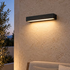 Applique LED noire avec lumière chaude sur le mur d’une terrasse abritée