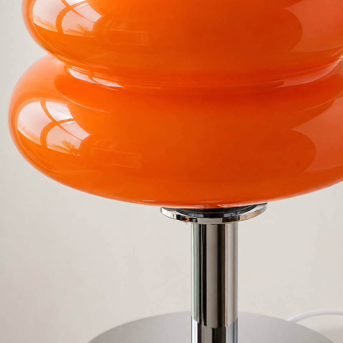 Détail de l’abat-jour en verre orange à deux niveaux et du pied chromé