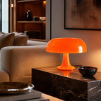 Lampe champignon orange allumée sur une console en bois foncé dans un salon