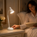 Femme lisant au lit, lampe à col flexible allumée orientée vers ses pages.