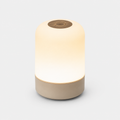 Lampe cylindrique allumée en lumière chaude, diffuseur blanc et base beige, fond neutre.