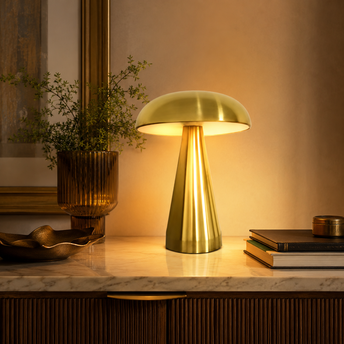 Lampe champignon dorée allumée sur une console en bois avec livres et cadre