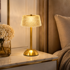 Lampe de chevet dorée effet cristal allumée près d’une fenêtre avec des fleurs séchées