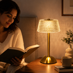 Lampe de chevet dorée effet cristal allumée à côté d’une personne lisant un livre