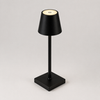 Lampe noire éteinte vue de face sur fond clair, pied fin et socle carré antidérapant.