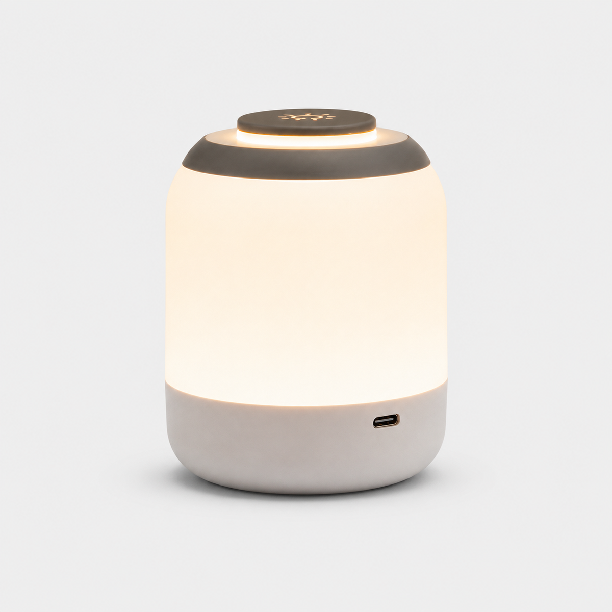 Lampe cylindrique allumée à diffuseur blanc et dessus gris, port de recharge visible.