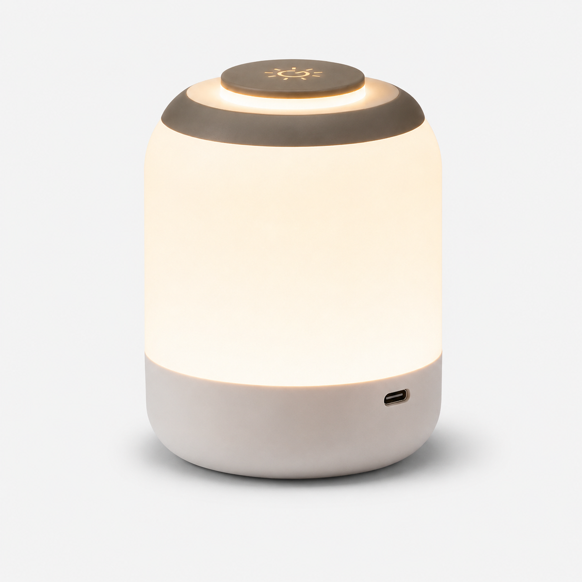 Lampe cylindrique allumée vue de trois quarts, base beige et prise de recharge latérale.